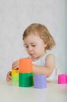 Small girl is building up a tower. Closeup photo