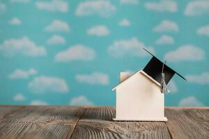 Black square academic cap on a handmade small house., Academic hat on a small wooden house. photo