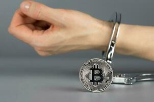 Bitcoin in front of hand in handcuff. photo