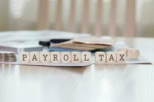Word PAYROLL TAX is composed of wooden letters. photo