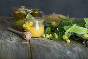 Linden blossoms honey in a glass bottle on a wooden surface. photo