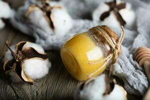 Cotton honey in a glass bottle on a wooden surface. photo