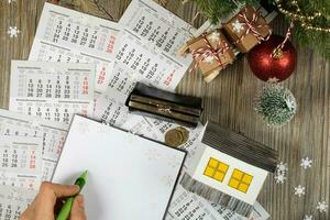 Blank sheet of paper and small paper house with coins on the New Year's background. photo