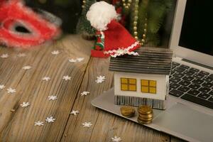 Small paper house with Santa Claus hat on it placed on laptop. photo