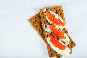 Cereal crispbread crackers with butter and red caviar. photo