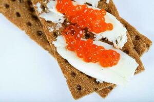 Cereal crispbread crackers with butter and red caviar. photo