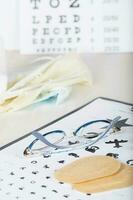 Eyeglasses for children on a eye chart close to eye pads. photo