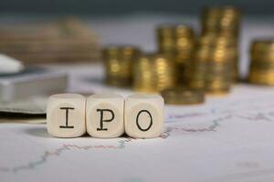 Abbreviation IPO composed of wooden letter. Stacks of coins in the background. photo