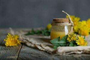 diente de león miel en un vaso botella en un pedazo de arpillera. foto