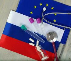 medicación, prueba tubos, dinero y estetoscopio en europeo y ruso banderas foto