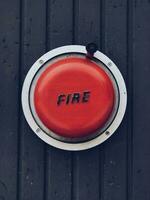 Red bell of an old fire alarm system on a wooden wall photo