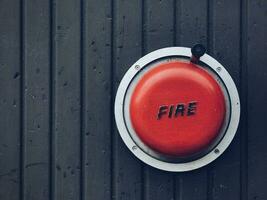 Red bell of an old fire alarm system on a wooden wall photo