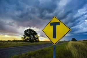 Road crossing warning sign with a stormy sky background, La Pampa province, Patagonia, Argentina. photo