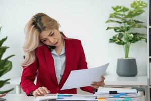 Consultant, Asian businesswoman working on the phone who discussion financial work and marketing business plan to increase company profits, ready to use computer and marketing planning documents. photo