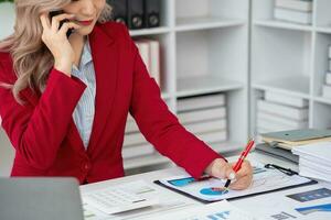 Consultant, Asian businesswoman working on the phone who discussion financial work and marketing business plan to increase company profits, ready to use computer and marketing planning documents. photo