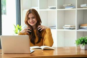 Happy latin girl college student watching distance online learning class, remote university webinar or having talk on laptop video call and use notebook to virtual meeting seminar at home or campus photo
