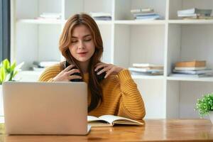 Happy latin girl college student watching distance online learning class, remote university webinar or having talk on laptop video call and use notebook to virtual meeting seminar at home or campus photo