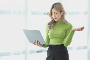 Portrait of a woman business owner showing a happy smiling face as he has successfully invested in her business using tablets and financial budget documents at work. photo