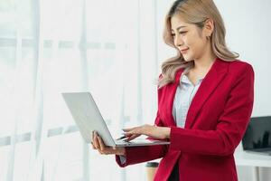 Portrait of a woman business owner showing a happy smiling face as he has successfully invested in her business using computers and financial budget documents at work. photo
