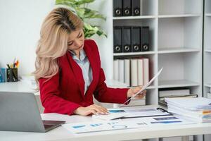 Consultant, Asian businesswoman working on the phone who discussion financial work and marketing business plan to increase company profits, ready to use computer and marketing planning documents. photo