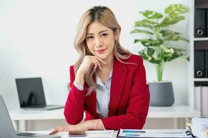 retrato de un mujer negocio propietario demostración un contento sonriente cara como él tiene exitosamente invertido en su negocio utilizando tabletas y financiero presupuesto documentos a trabajar. foto