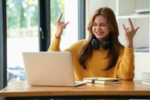 Happy latin girl college student watching distance online learning class, remote university webinar or having talk on laptop video call and use notebook to virtual meeting seminar at home or campus photo