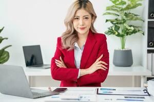 Portrait of a woman business owner showing a happy smiling face as he has successfully invested in her business using tablets and financial budget documents at work. photo