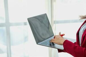 Portrait of a woman business owner showing a happy smiling face as he has successfully invested in her business using computers and financial budget documents at work. photo