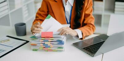 business documents on office table with smart phone and digital tablet and graph financial and woman working at modern office photo