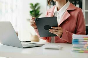 Hands of woman using mobile phone in modern office with laptop and digital tablet at office photo