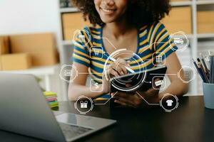 African Woman hand using a laptop, smartphone and tablet and writing notebook at the office of her business online shopping. In home with virtual icon photo