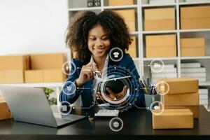 African Woman hand using a laptop, smartphone and tablet and writing notebook at the office of her business online shopping. In home with virtual icon photo