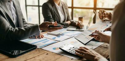 Business documents on office table with smart phone and calculator digital tablet and graph business with social network diagram and two colleagues discussing data working in the office photo