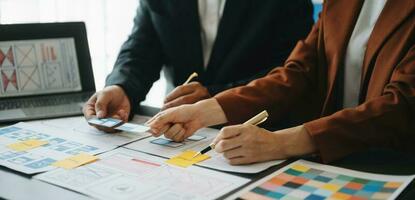 UX developer and ui designer brainstorming about mobile app interface wireframe design with customer breif and color code at office. photo