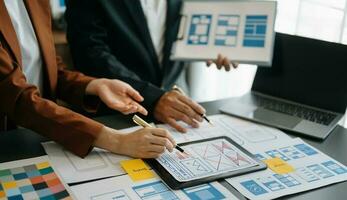 UX developer and ui designer brainstorming about mobile app interface wireframe design with customer breif and color code at office. photo