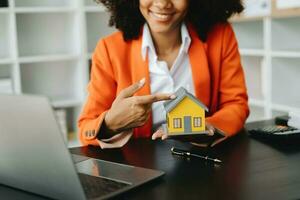 agente de bienes raíces que presenta y consulta al cliente para la toma de decisiones firmar un acuerdo de formulario de seguro, modelo de hogar, en relación con la oferta de préstamo hipotecario foto