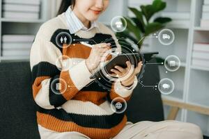 Woman hand using a laptop, smartphone and tablet and writing notebook at the office of her business online shopping. In home with virtual icon photo