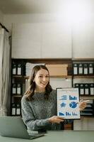 Young beautiful woman typing on tablet and laptop while sitting at the working wooden table office photo