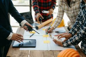 reunión de trabajo en equipo de ingenieros, trabajo de dibujo en la reunión de planos para el trabajo del proyecto con un socio en la construcción de modelos en la oficina de la empresa. equipo profesional de la industria asiática foto