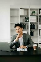 Young business man working at office with laptop, tablet and taking notes on the paper. photo