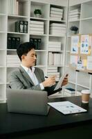 Young business man working at office with laptop, tablet and taking notes on the paper. photo