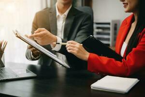 Business documents on office table with smart phone and calculator digital tablet and graph business with social network diagram and two colleagues discussing data working in the office photo