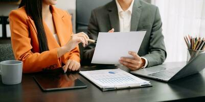 Business documents on office table with smart phone and calculator digital tablet and graph business with social network diagram and two colleagues discussing data working in the office photo