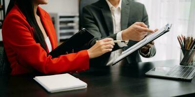 Business documents on office table with smart phone and calculator digital tablet and graph business with social network diagram and two colleagues discussing data working in the office photo
