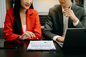 Business documents on office table with smart phone and calculator digital tablet and graph business with social network diagram and two colleagues discussing data working in the office photo