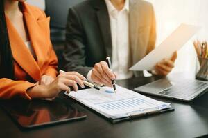 Business documents on office table with smart phone and calculator digital tablet and graph business with social network diagram and two colleagues discussing data working in the office photo