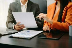 Business documents on office table with smart phone and calculator digital tablet and graph business with social network diagram and two colleagues discussing data working in the office photo