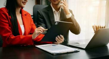 Business documents on office table with smart phone and calculator digital tablet and graph business with social network diagram and two colleagues discussing data working in the office photo