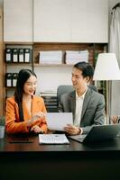 Two Asian businesswoman discuss investment project working and planning strategy with tablet laptop computer in  office. photo