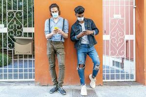 couple of multiracial friends with face masks using smartphones photo